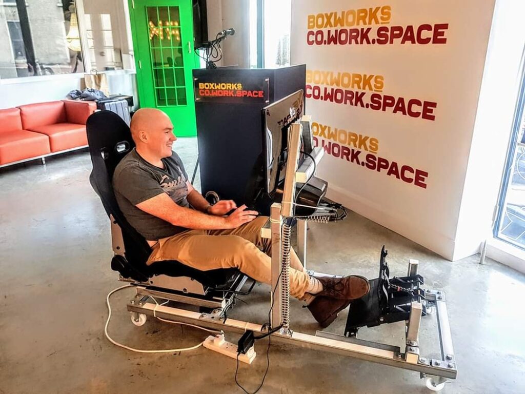 Man using a driving simulator setup at Boxworks Co-Working Space.