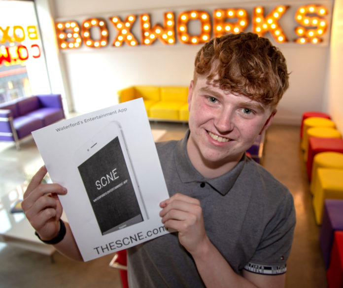 Young man holding an SCNE app poster at Boxworks.